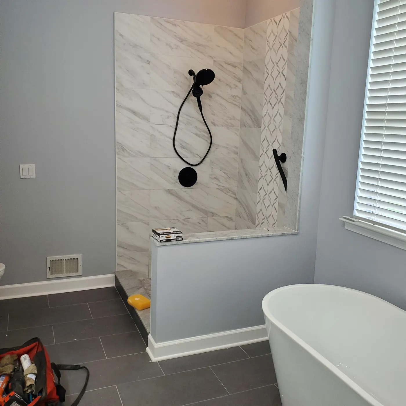 Bathroom remodel with marble tile shower surround and freestanding tub in progress