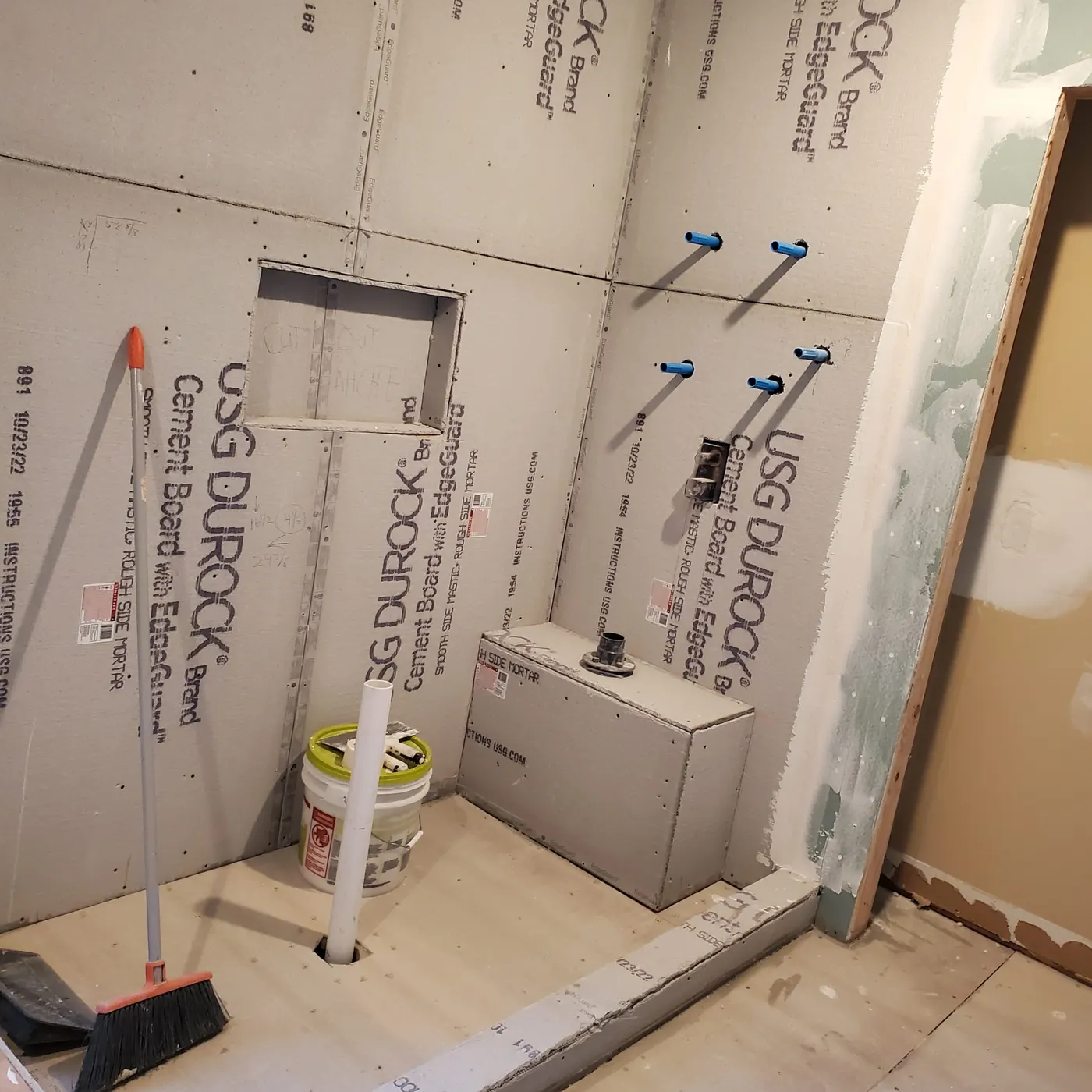 Shower rough-in stage with cement board, new supply lines and curb before tile