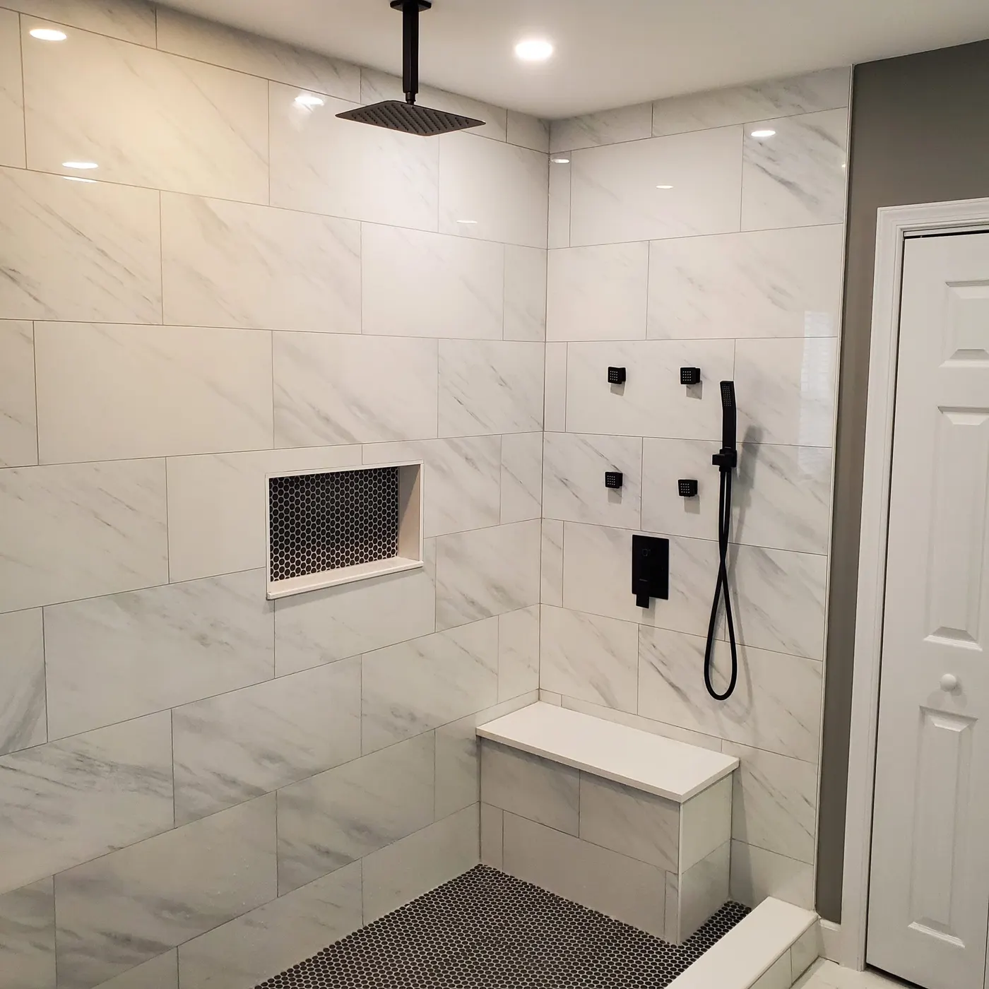 Marble-look tile shower with ceiling-mounted rain head and bench