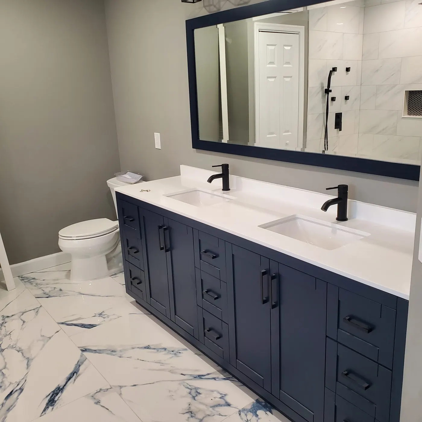 Navy double vanity with quartz top installed in a full bathroom remodel